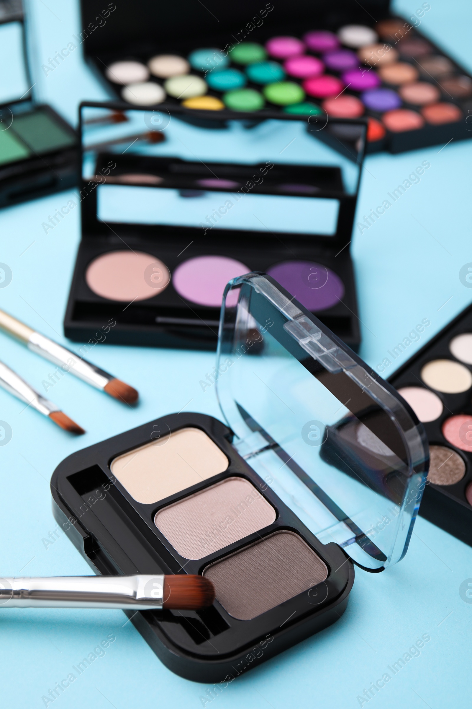 Photo of Beautiful eye shadow palettes and brushes on light blue background