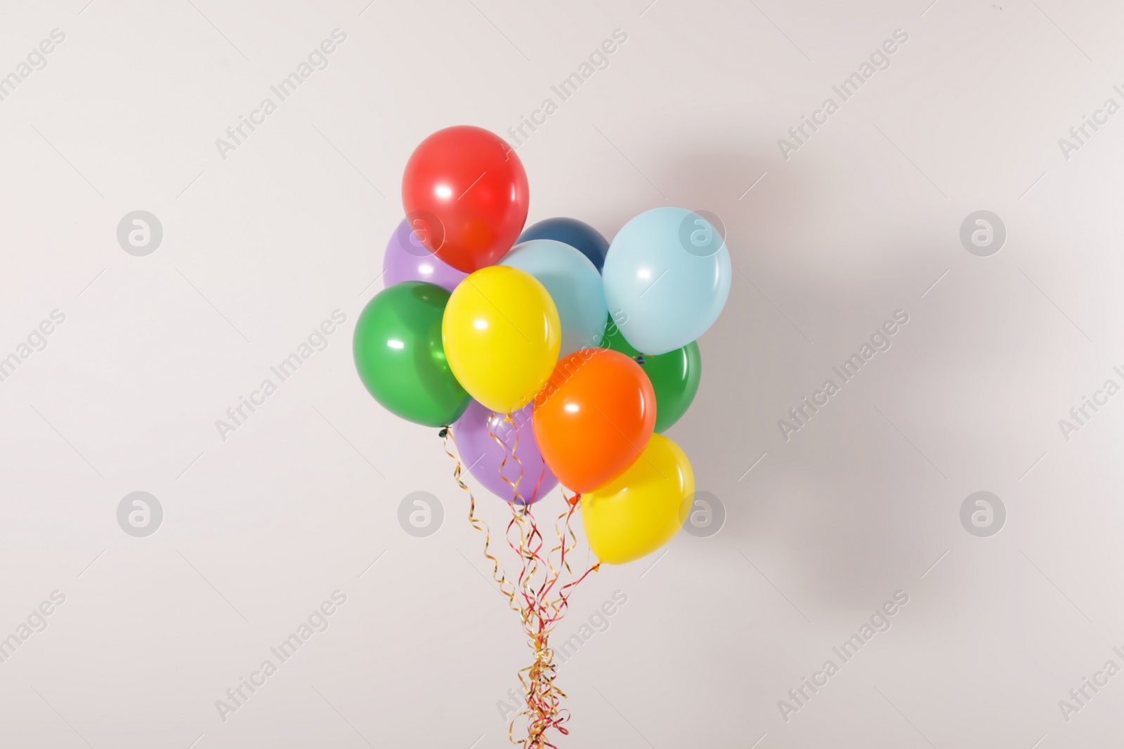 Photo of Bunch of bright balloons on light background. Celebration time
