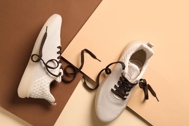 Stylish sneakers with brown shoe laces on color background, flat lay