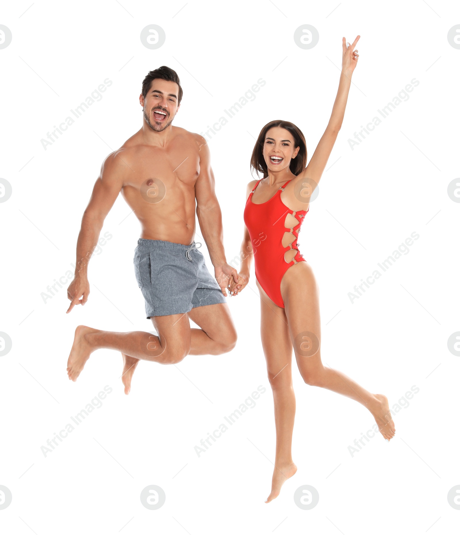 Photo of Young attractive couple in beachwear jumping on white background