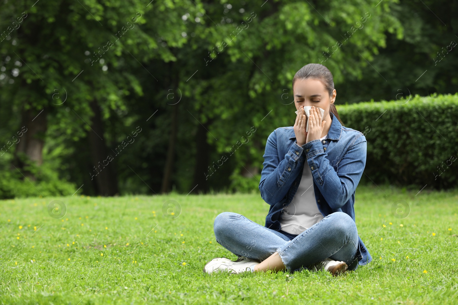 Photo of Woman suffering from seasonal spring allergy on green grass in park. Space for text