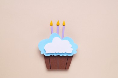 Photo of Birthday party. Paper cupcake with candles on beige background, top view