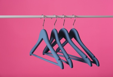 Photo of Metal rack with clothes hangers on color background