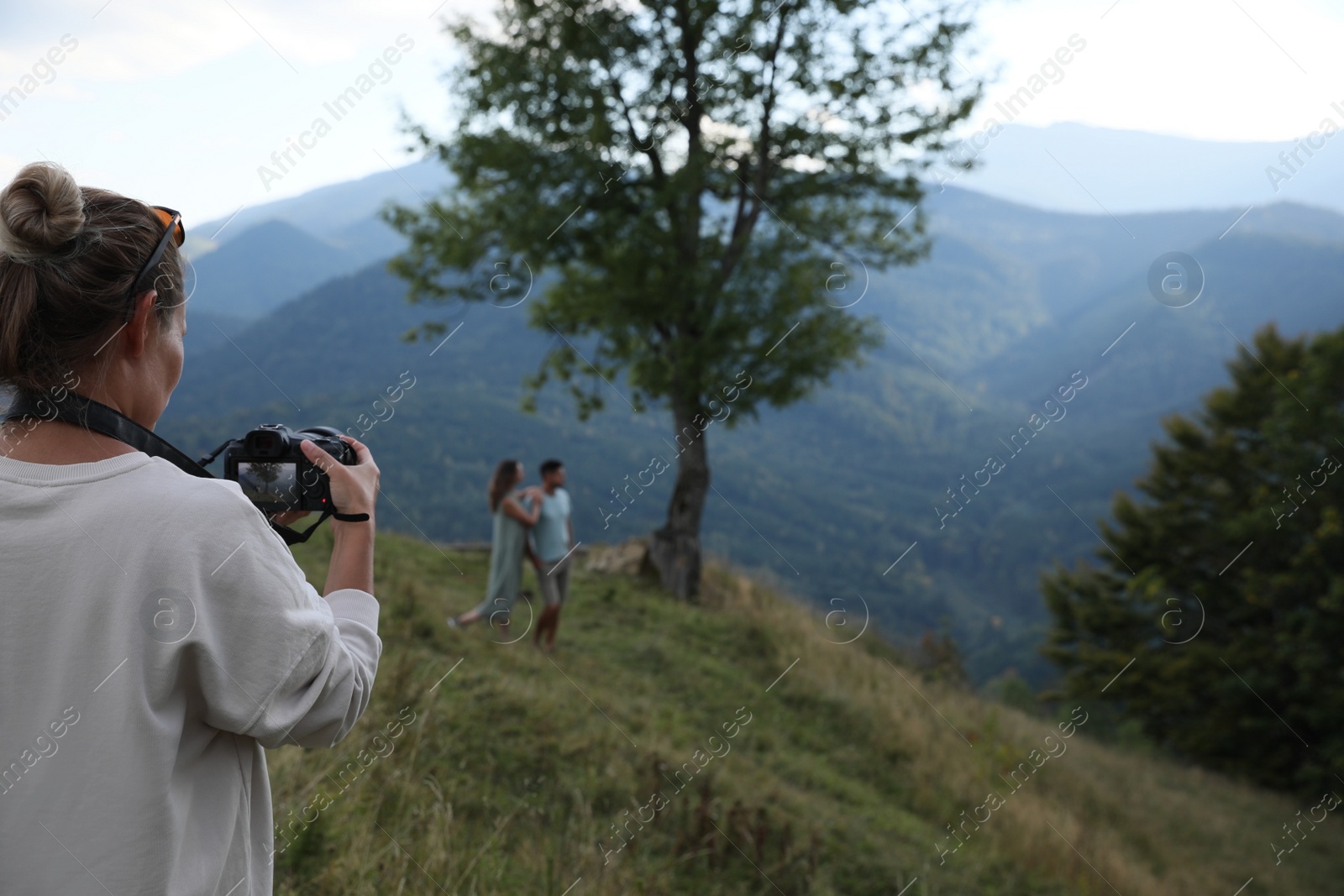 Photo of Professional photographer taking picture of couple in mountains