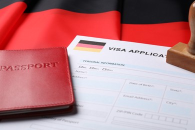 Immigration to Germany. Visa application form, passport and stamp on flag, closeup