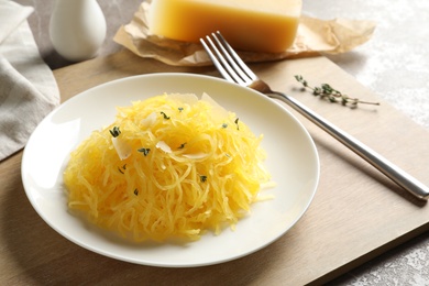 Photo of Plate with cooked spaghetti squash on wooden board