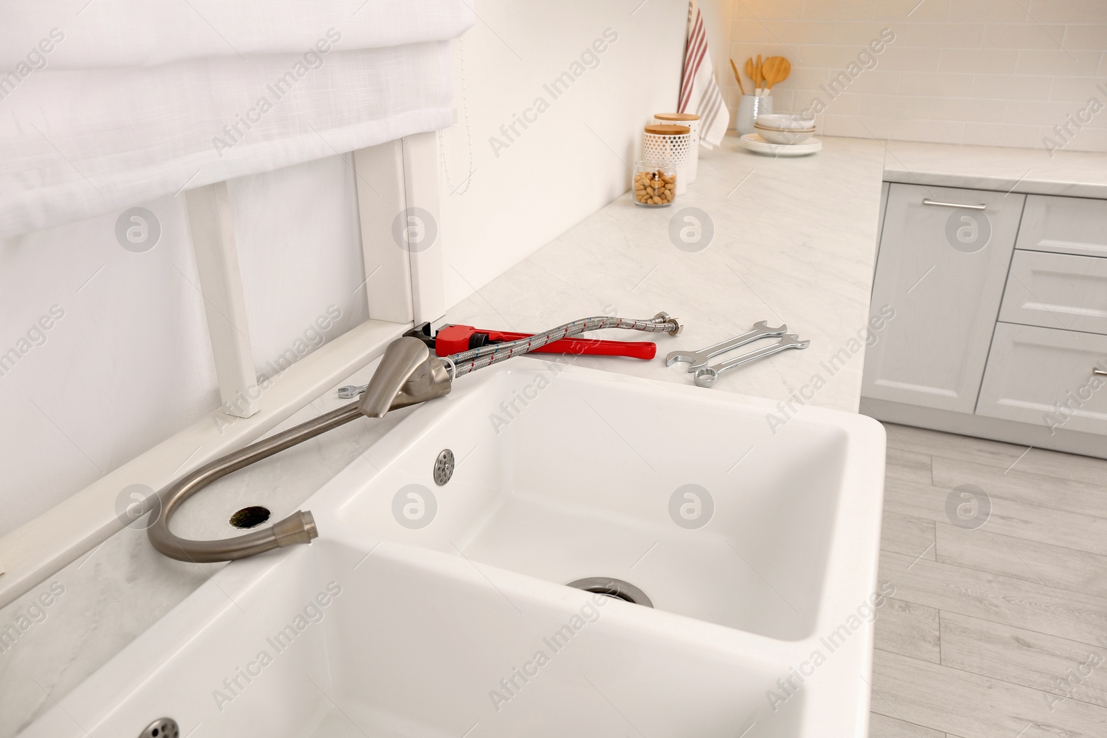 Photo of Plumber's tools and water tap ready for installation near sink on countertop in kitchen