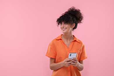 Photo of Happy woman sending message via smartphone on pale pink background, space for text