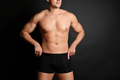 Photo of Man with sexy body on black background, closeup. Space for text