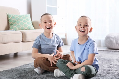 Photo of Portrait of cute twin brothers sitting on floor in living room