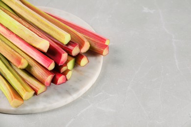 Fresh ripe rhubarb stalks on light grey table, closeup. Space for text