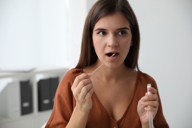 Woman taking sample for DNA test indoors