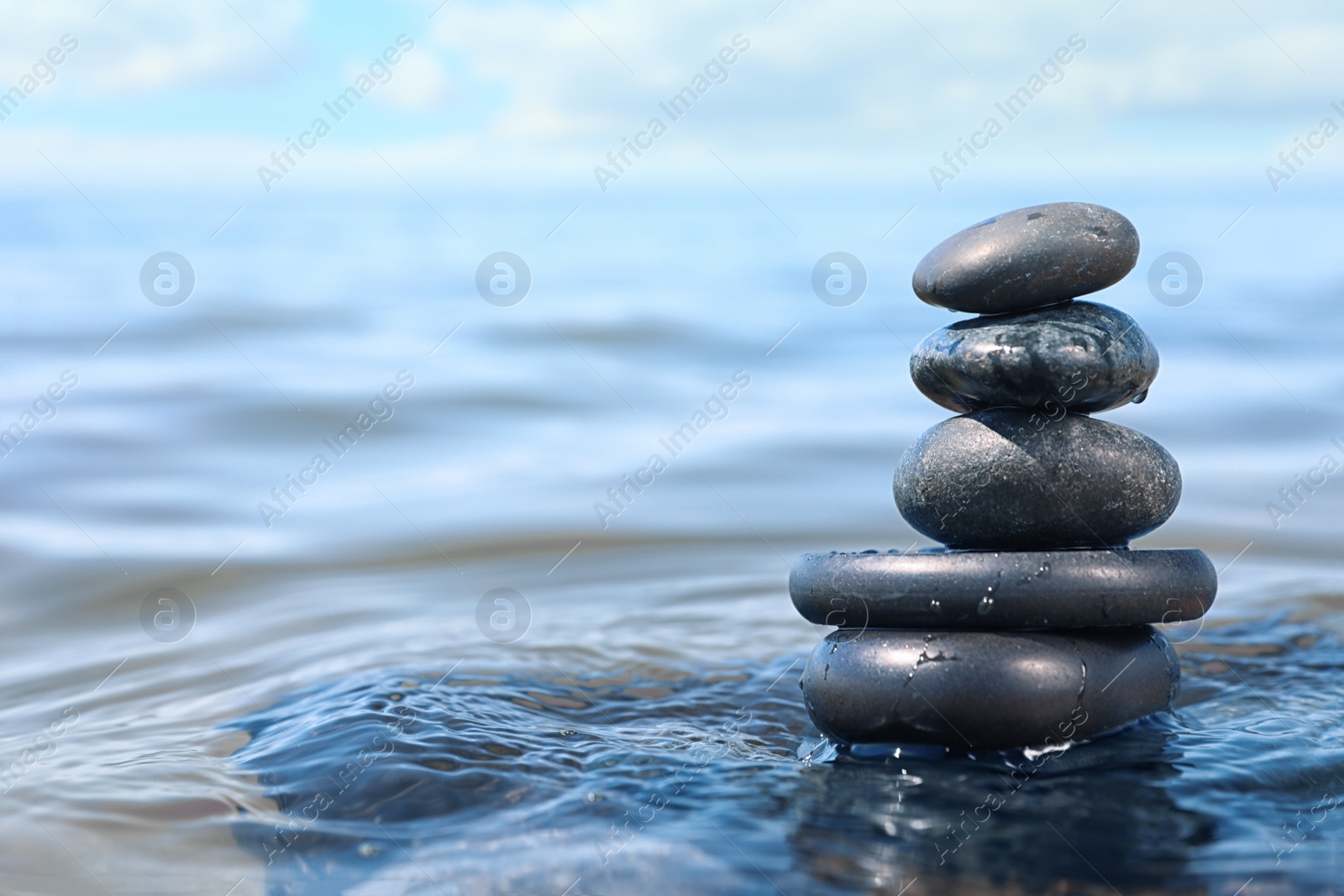 Photo of Stack of stones in sea water, space for text. Zen concept