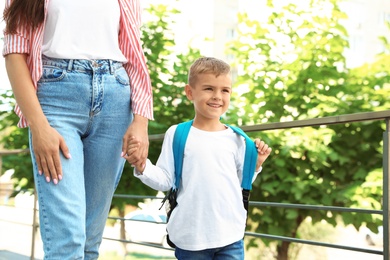 Young mother taking her little child to school outdoors