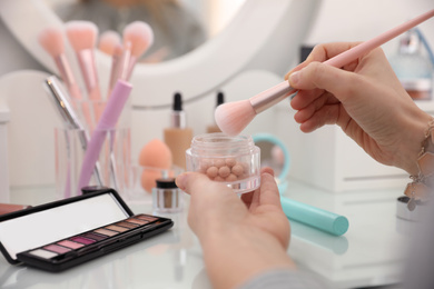 Photo of Woman applying makeup at dressing table, closeup