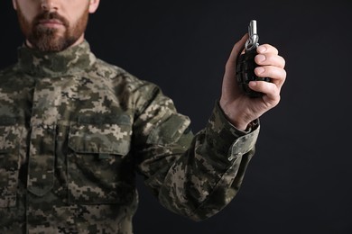 Photo of Soldier holding hand grenade on black background, closeup. Military service