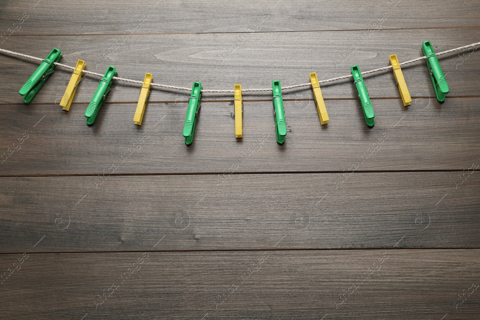 Photo of Colorful plastic clothespins and rope on wooden background. Space for text