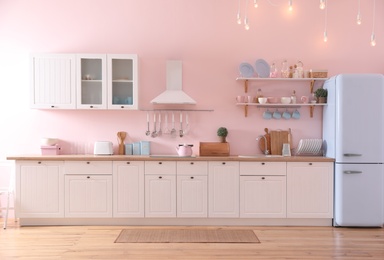 Photo of Stylish pink kitchen interior with modern furniture and fridge