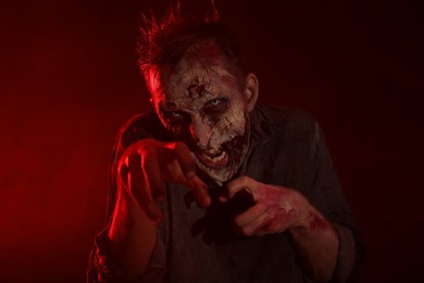 Photo of Scary zombie on dark background. Halloween monster