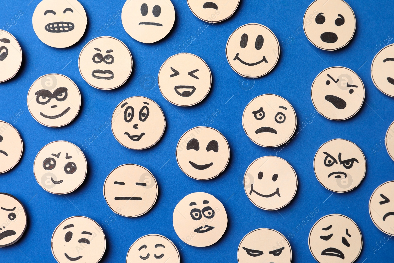 Photo of Many faces with different emotions on blue background, flat lay