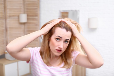 Emotional woman with hair loss problem in bathroom