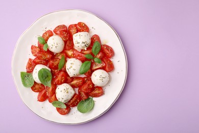Tasty salad Caprese with tomatoes, mozzarella balls and basil on pink background, top view. Space for text