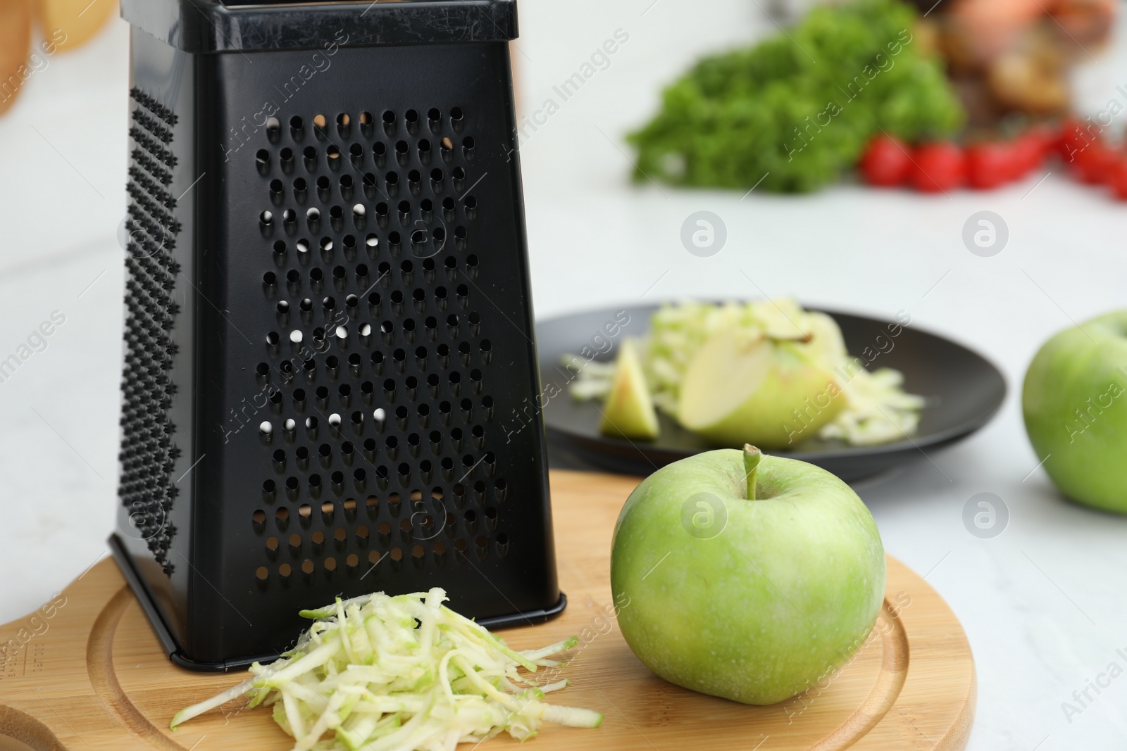 Photo of Grater and fresh ripe apple on wooden board, closeup