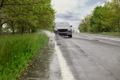 Photo of Wet suburban road with car on rainy day
