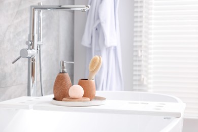 Photo of Different personal care products and accessories on bath tub in bathroom, space for text