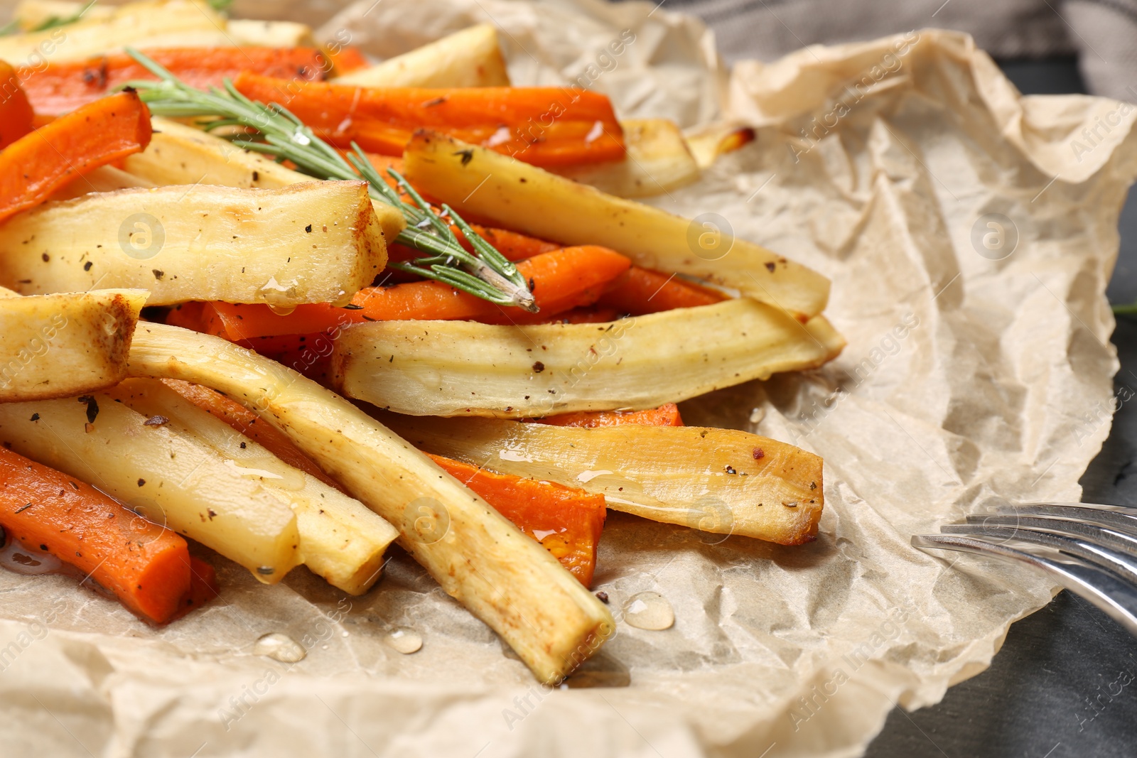 Photo of Tasty baked parsnip and bell pepper on parchment, closeup