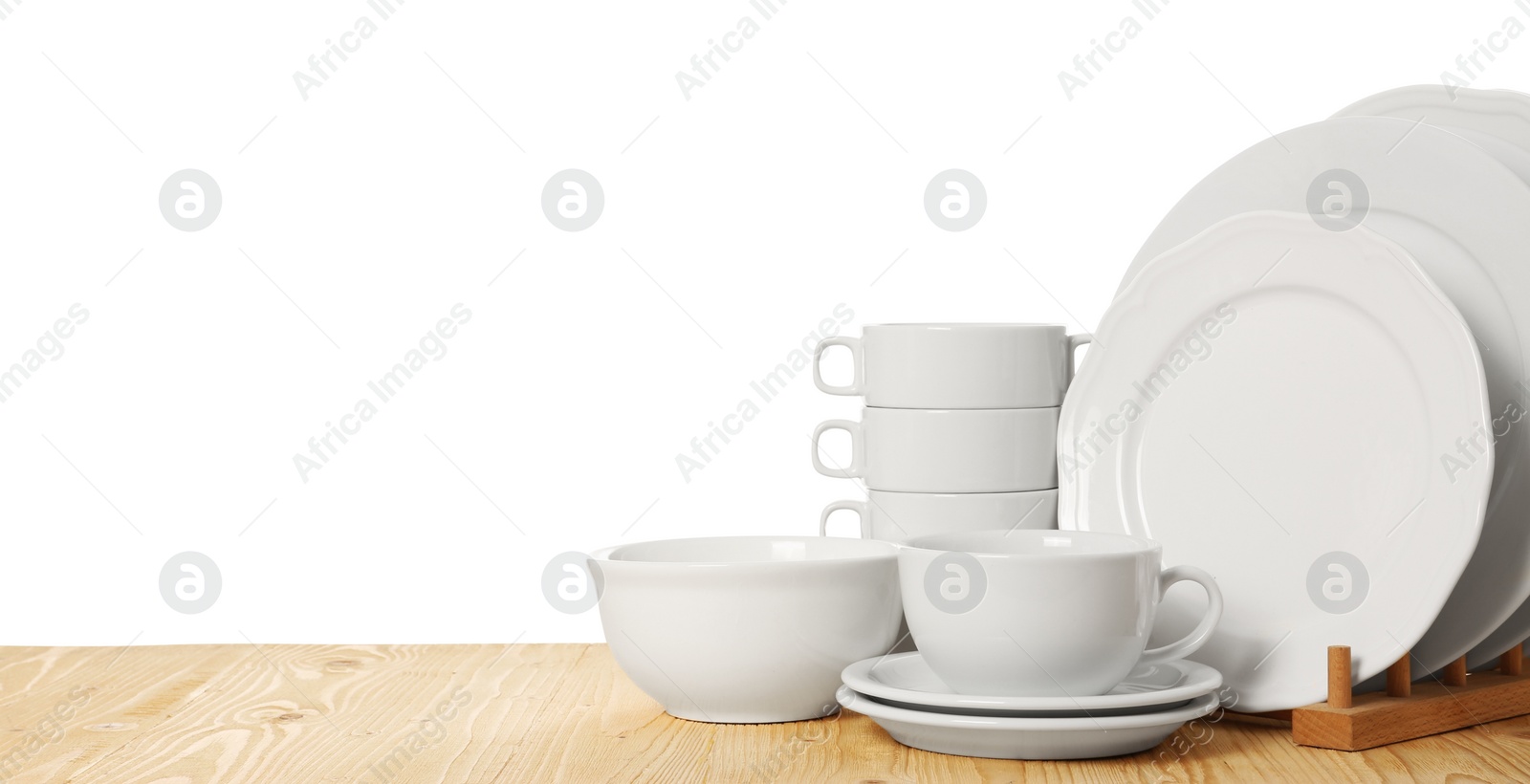 Photo of Set of different clean dishware on wooden table against white background