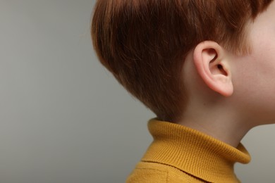 Photo of Hearing problem. Little boy on grey background. closeup. Space for text