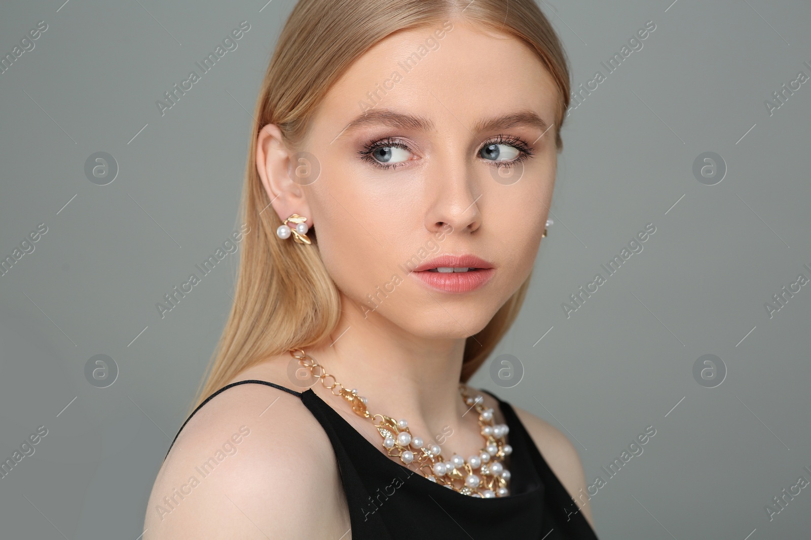 Photo of Beautiful young woman with elegant jewelry on gray background