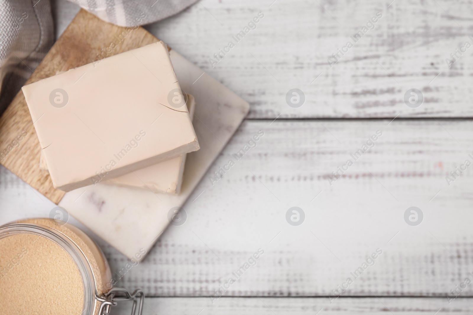 Photo of Blocks of compressed yeast on white wooden table, flat lay. Space for text