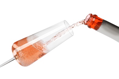 Rose champagne pouring from bottle into glass isolated on white