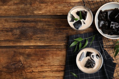 Photo of Glasses of milk with grass jelly on wooden table, flat lay. Space for text