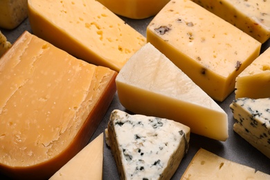 Photo of Different kinds of delicious cheese on stone background, closeup