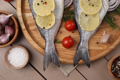 Raw dorado fish, lemon, spices and tomatoes on wooden table, flat lay