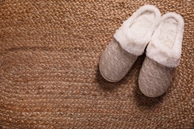 Photo of Pair of warm stylish slippers on wicker carpet, top view. Space for text