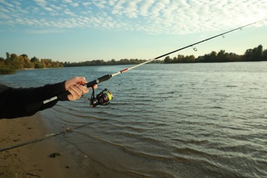 Photo of Fisherman with rod fishing at riverside, closeup. Space for text