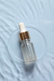 Bottle of cosmetic serum and water on light blue background, top view