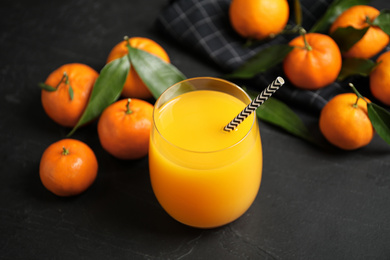 Photo of Glass of fresh tangerine juice and fruits on black table