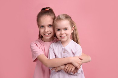 Photo of Portrait of cute little sisters on pink background