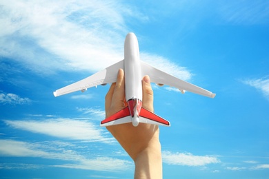 Photo of Woman holding toy airplane against blue sky, closeup