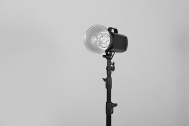 Flashlight with reflector on grey background, space for text. Professional photographer's equipment