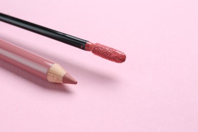 Lip pencil and brush of liquid lipstick on pink background, space for text. Cosmetic products