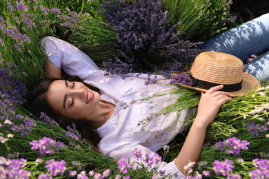 Young woman lying in lavender field on summer day