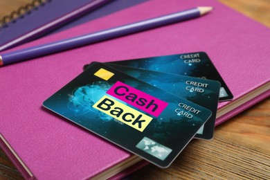Image of Notebooks, pencils and cashback credit cards on wooden table, closeup