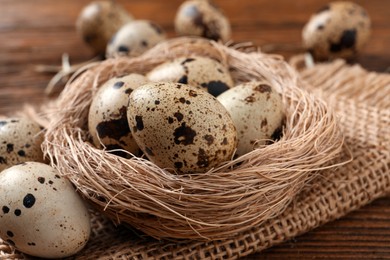 Photo of Nest and quail eggs on wooden table, closeup