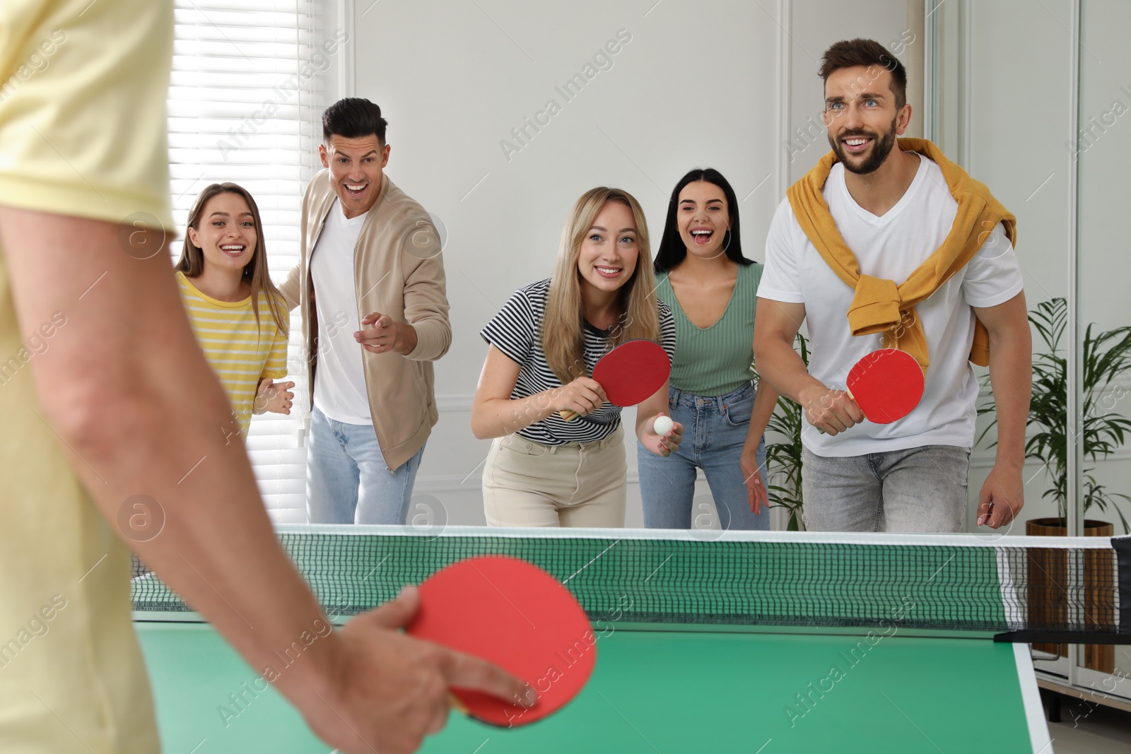 Photo of Happy friends playing ping pong together indoors